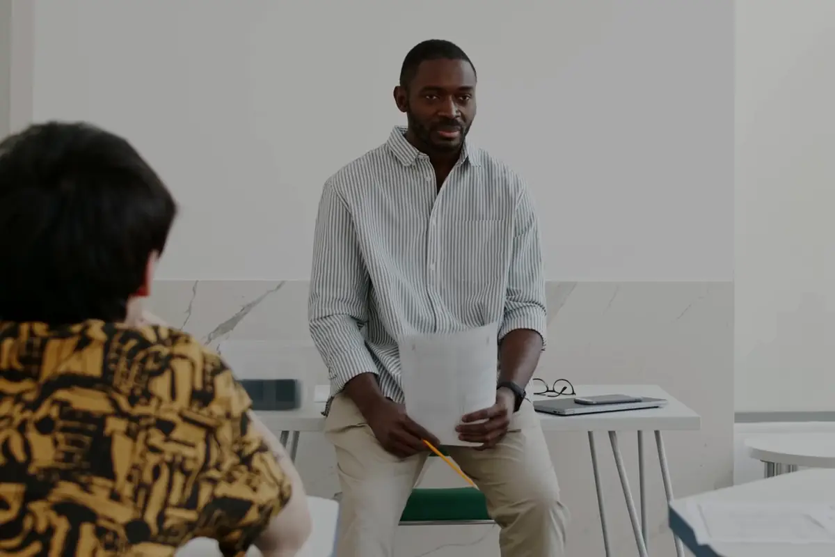 A mentor talking with a small group of teenagers in a classroom
